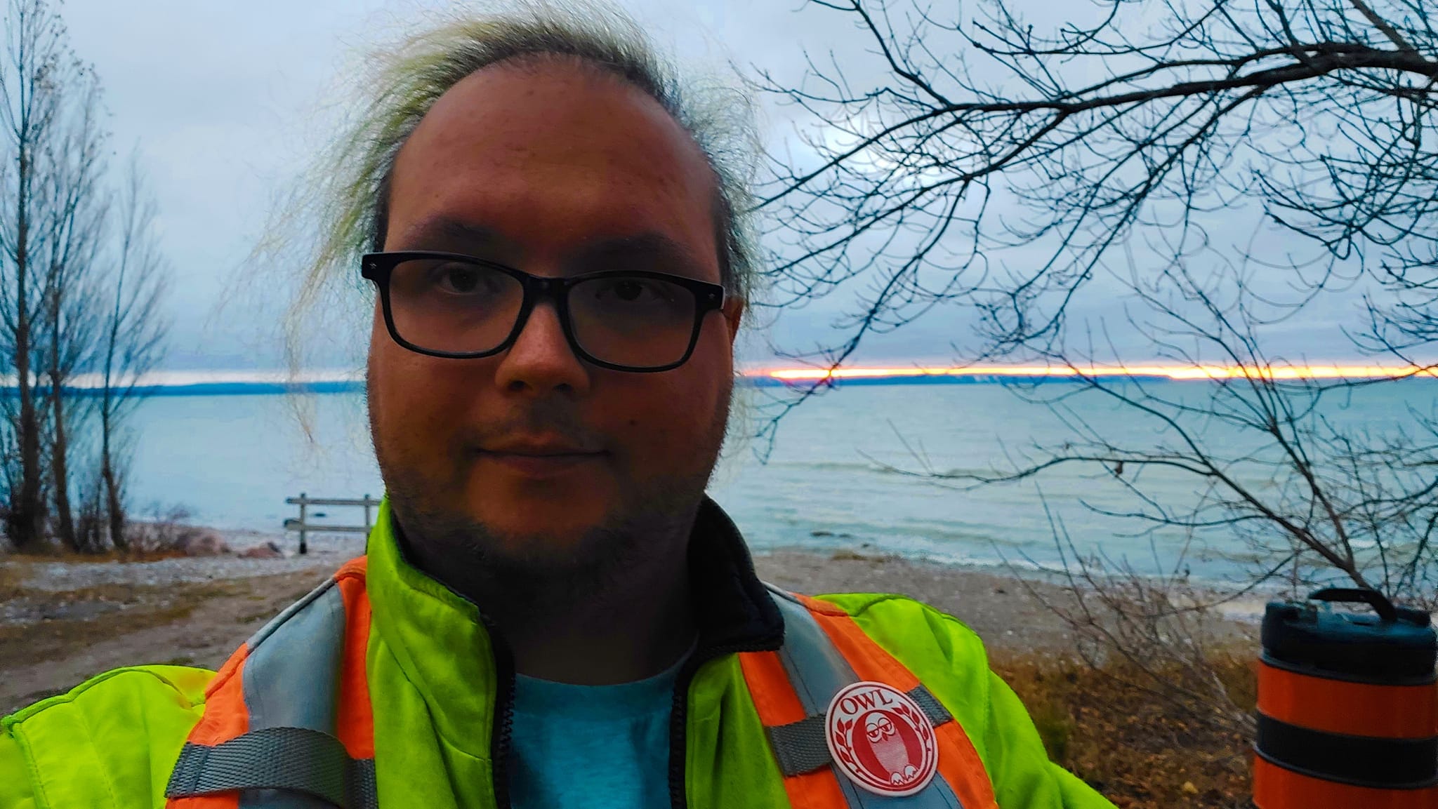 A man wearing a high visibility winter coat stands in front of Georgian Bay